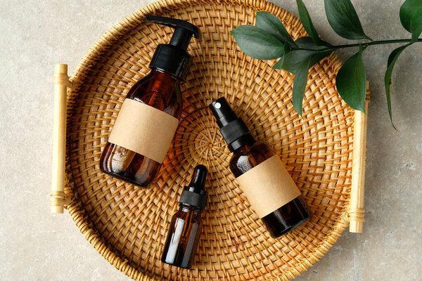 Amber glass cosmetic bottles set in rattan container on table in bathroom. SPA natural organic beauty products for personal hygiene, toiletry cosmetics.