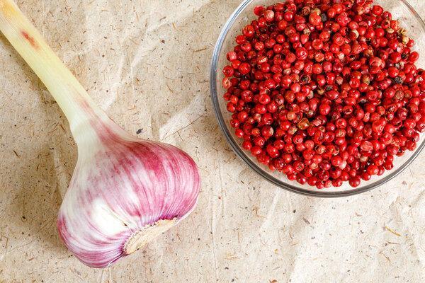 Fresh garlic and Brazilian pepper on craft paper. Garlic is used in the season of colds, viruses, flu to increase local immunity, health, vitamins, and Wellness. Selective focus. Flat Lay