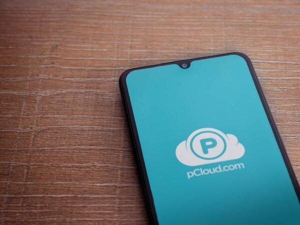 以色列罗德- 2023年7月16日：pCloud应用在木制背景的智能手机上启动屏幕。带有复制空间的顶视图平面布局.