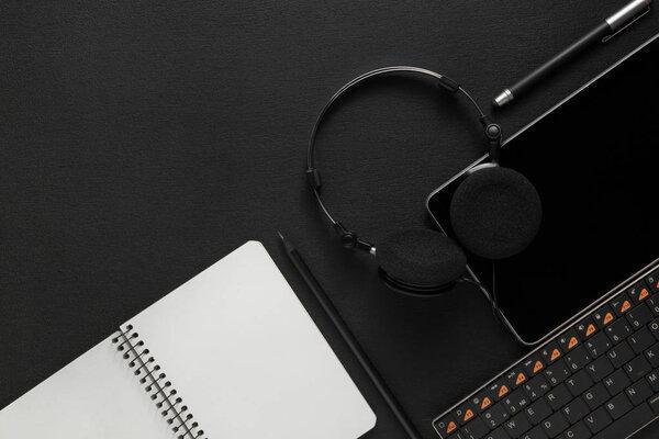 tablet with headphones near the keyboard on dark background