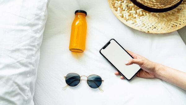 Top view blank screen of smartphone on room and hat, glasses, During leisure time. The concept of using the phone is essential in everyday life.