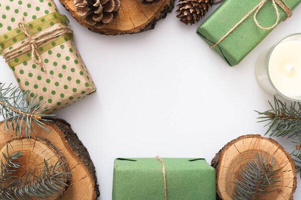 Zero waste Christmas. Frame made of pine cones, branches, candle, tree rings, crafted gifts with no plastic on white table. Top view, close up, copy space, background, flat lay.