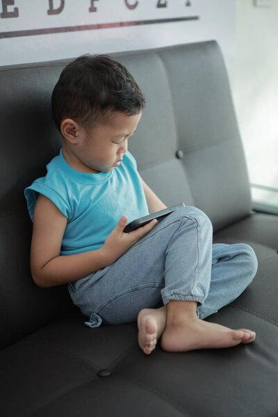 孩子们在沙发上玩游戏，孩子们用电话 