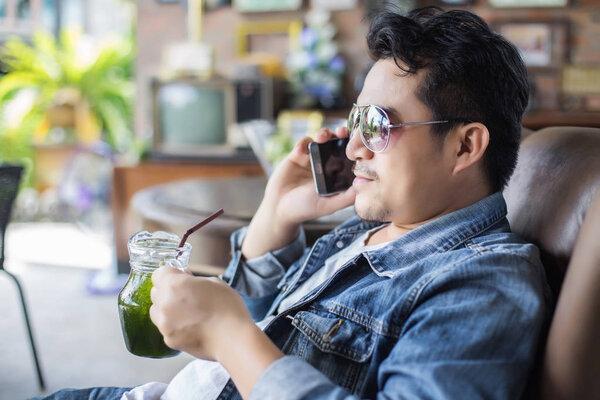 Young man with smartphone smiling relaxing at cafe.