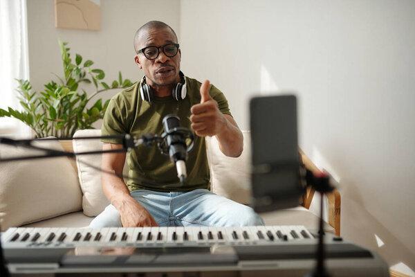 Positive music teacher streaming himself explaining how to play synthesizer
