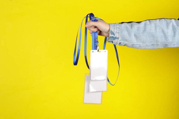 Hand holding Identification white blank id cards on yellow background