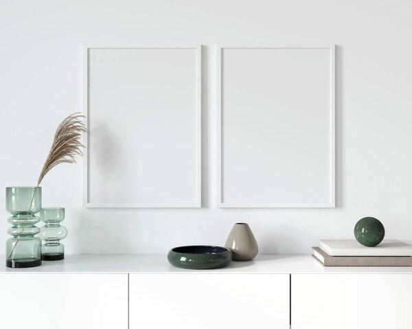 A poster with two white frames standing on a chest of drawers near a green glass vase with a wheat branch, books and a stone ball against the background of a white wall / 3D illustration, 3d render 