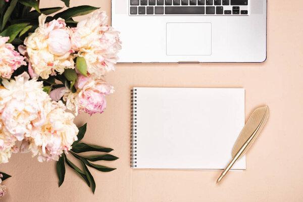 Workspace with keyboard laptop and peony flowers. Top view on a pink desk, flat lay with copy space. Office business concept