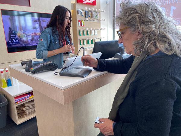 Fidenza, Italy - May 2023 Vodafon shop franchise in Fidenza, Italy.与移动通信提供商签订的数字平板电脑合同中的高级妇女签名.