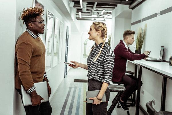 Smiling long-haired woman talking to her African American colleague