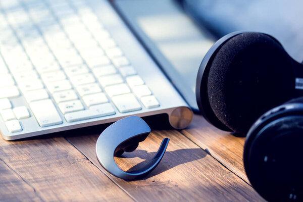 Headphones and laptop are on the wooden table outdoor. Technology and lifestyle concept