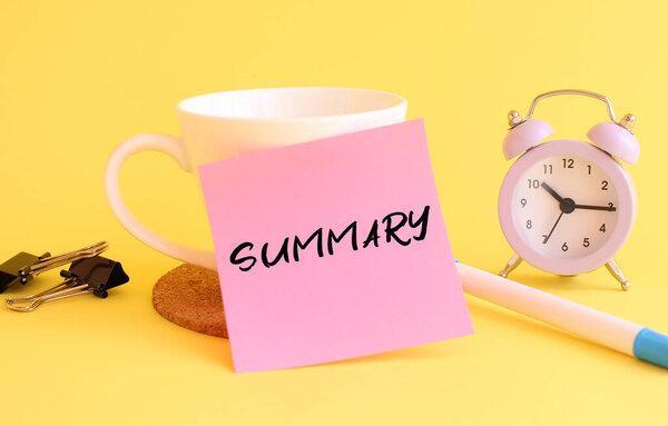 Pink paper with the text SUMMARY on a white cup. Clock, pen on a yellow background. Design concept.