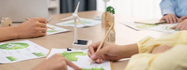 Green business meeting represented renewable energy. Skilled businesspeople discuss green business investment at table with environmental documents. Closeup. Focus on hand. Delineation.