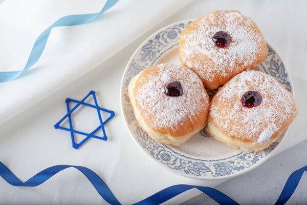 Hanukkah symbol jewish food holiday image of donut with jam sugar powder on the white napkin and David star