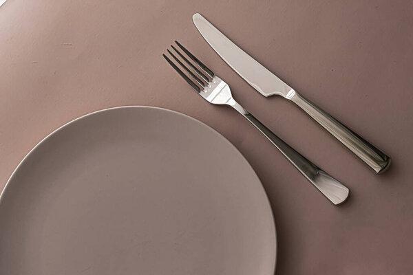 Empty plate and cutlery as mockup set on brown background, top tableware for chef table decor and menu branding