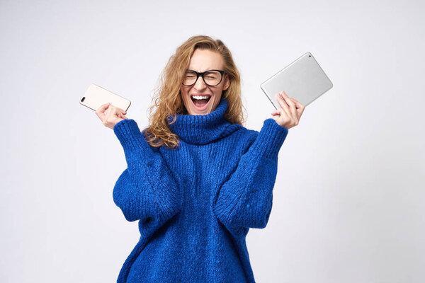 angry girl on a white background with a phone and a tablet in her hands