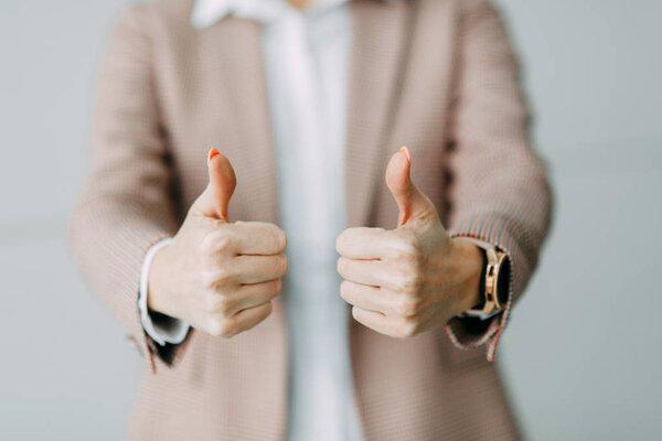 The girl is holding thumbs up. Showing success and right choice in business.
