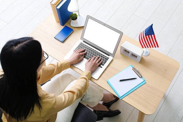 Woman using laptop on table with USA flag
