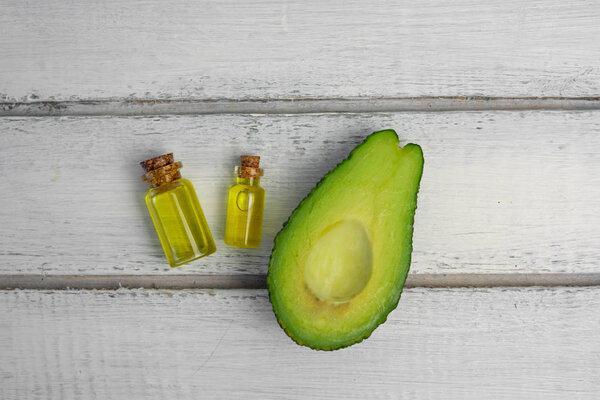 Natural products for skin care. Avocado oil in bottles near sliced avocado on grey background top view copy space