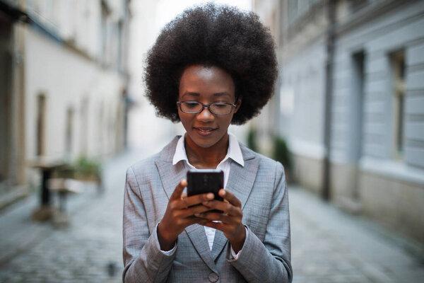 African business lady using smartphone on street