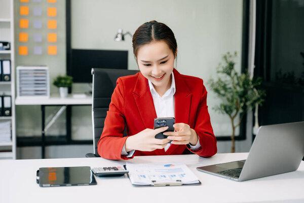 Young attractive Asian businesswoman using smartphone in modern office