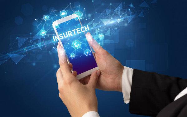 带有INSURTECH铭文的女性手持智能手机，现代技术概念