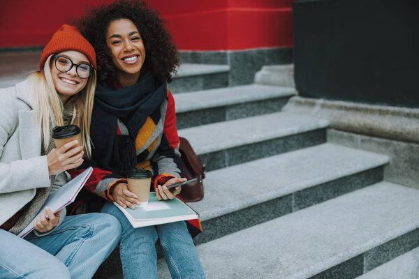 Young Caucasian and Afro American females smiling wide