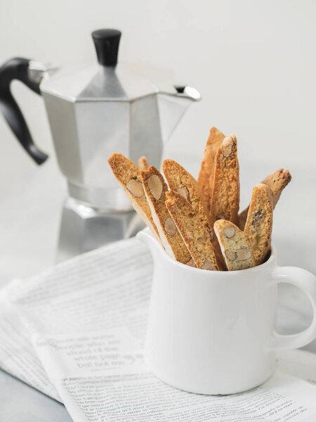 Biscotti traditional Italian almond dessert with Mocha coffee pot on newspaper, close up with copy space