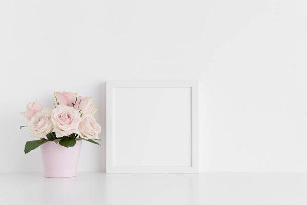 White square frame mockup with pink roses in a pot on a white table.