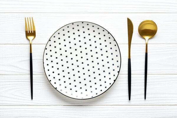 empty white round plate with black peas, fork, knife, spoon on wooden table Top view Flat lay Dishes for breakfast, lunch or dinner Mock up.