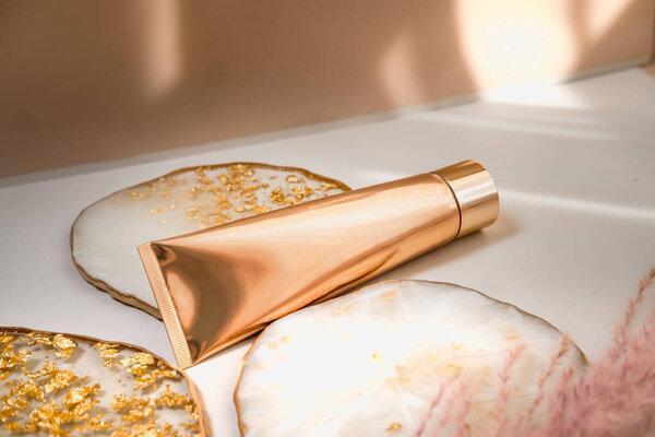 Golden cosmetic tube light pastel color background, lights and shadows. Minimal styling, still life. Beauty blogging, branding layout,  skin care ad mock up, copy space for text 