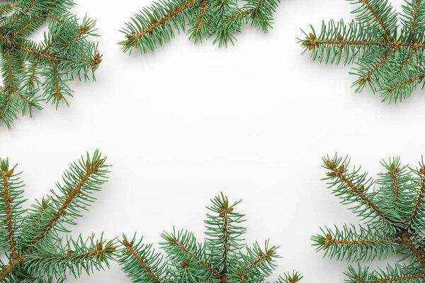 Holiday frame of Christmas decorative fir branches on white background, top view, flat lay.
