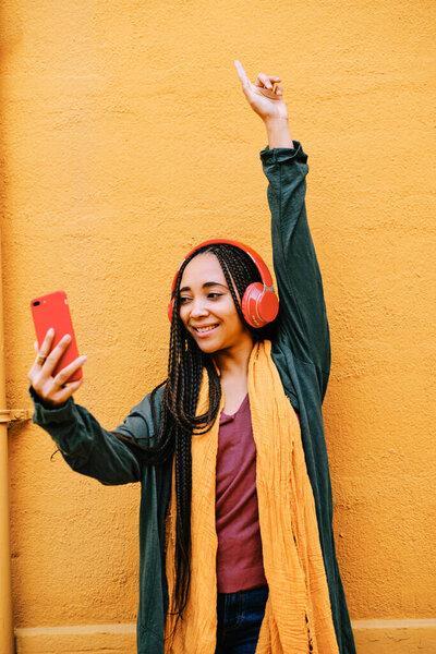 happy black woman with braids listening music with headphones