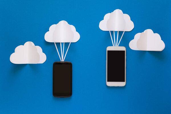 Network connection and cloud storage technology concept. Data communications and cloud computing network concept. Smart phone flying on paper cloud. Origami. Paper cut. Top view