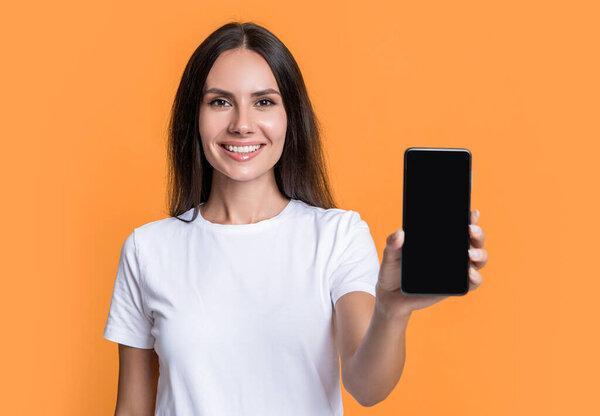 Presenting product with copy space, selective focus. Happy woman showing mobile phone. Woman smiling presenting mobile device. Mobile technology. Mobile communication.