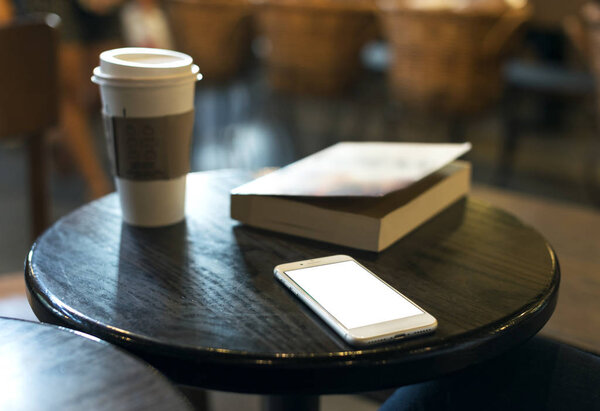 在有一本书的咖啡馆里, 木桌上的智能手机.