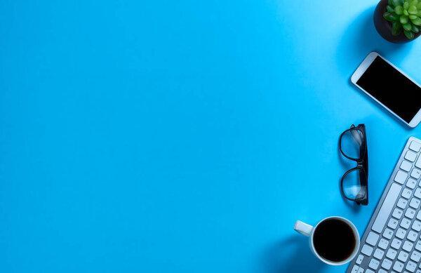 Basic work or school supplies with morning coffee on a blue desk top setting 