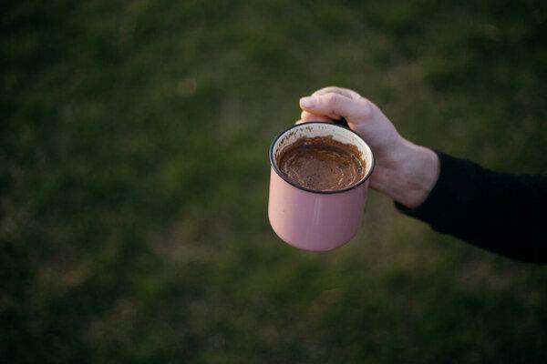 a cup of coffee stands on a wooden table in the garden