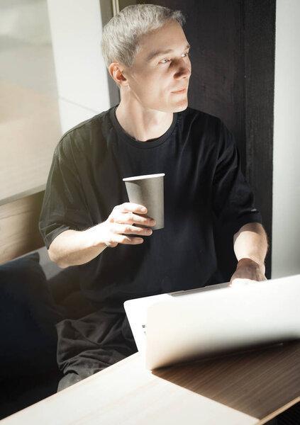 Young man working on laptop and drinking coffee.