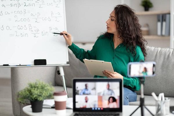 Math teacher pointing on board, giving virtual lecture to students
