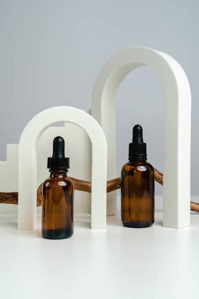 Massage oils in a dark glass jar. Essence for skin health against the backdrop of arches. Trendy style. Geometric figures. Photo in monochrome style. Mockup for your product. Conceptual photo.