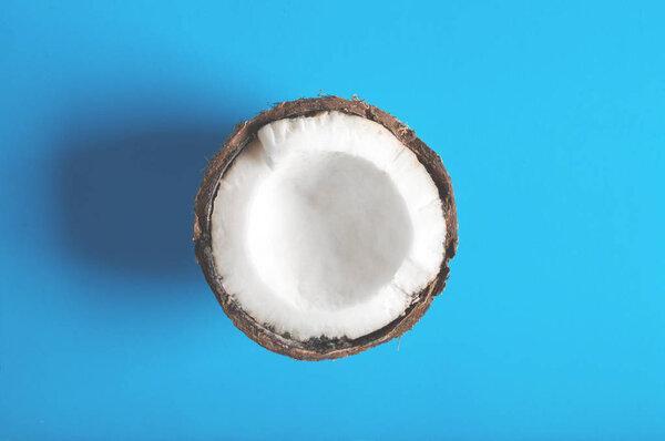 Half of coconut on a blue minimalistic background