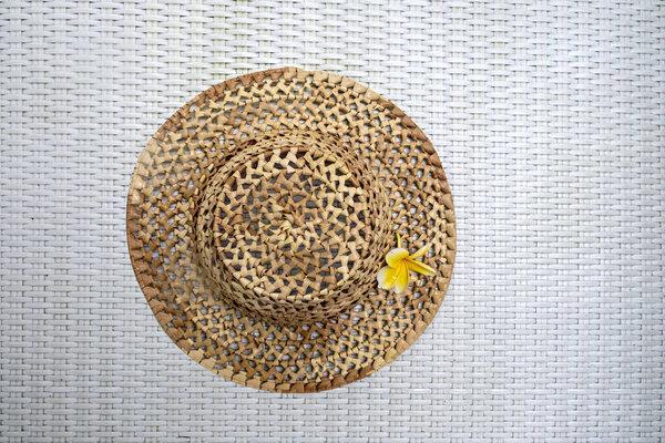 Travel. Summer mockup. Straw hat on white textured background with frangipani flower. View from above. The concept of holidays, vacations and travel