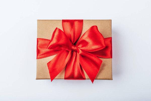 Cardboard gift box with red bow on white background.