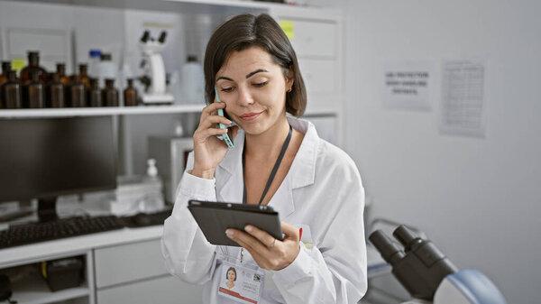年轻美丽的惊慌失措的女科学家用触摸板在实验室用智能手机交谈