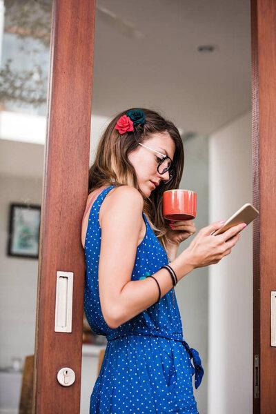Young adult woman using smartphone in a modern home.