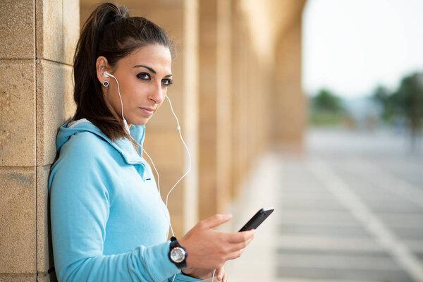 Young female brunette standing with cell phone and head set with hair pulled back
