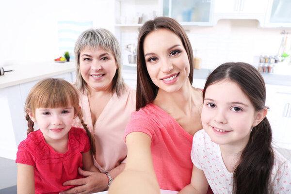 Mother, granny and girls taking selfie at kitchen