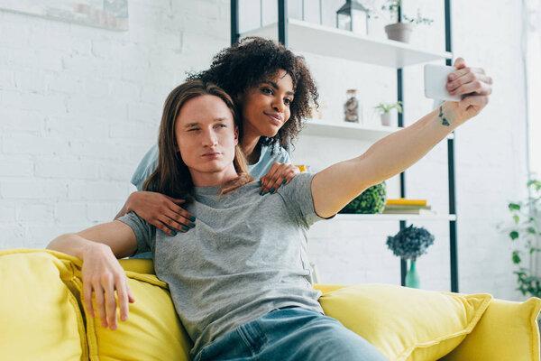 young interracial couple taking selfie on smartphone 