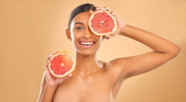 Indian woman, grapefruit and beauty with face in portrait, natural cosmetics and organic treatment on studio background. Skincare, healthy glow and female smile with fruit product, skin and mockup.